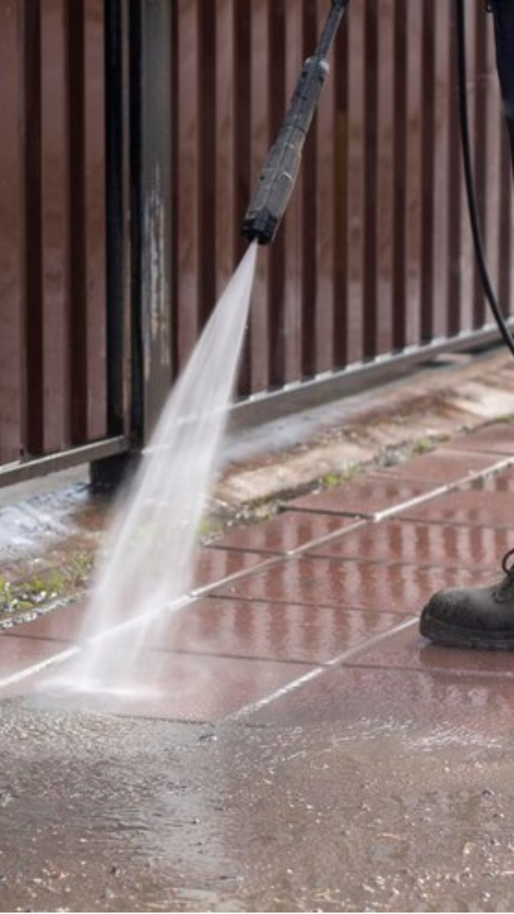 Person using a pressure washer to clean outdoor tiled flooring