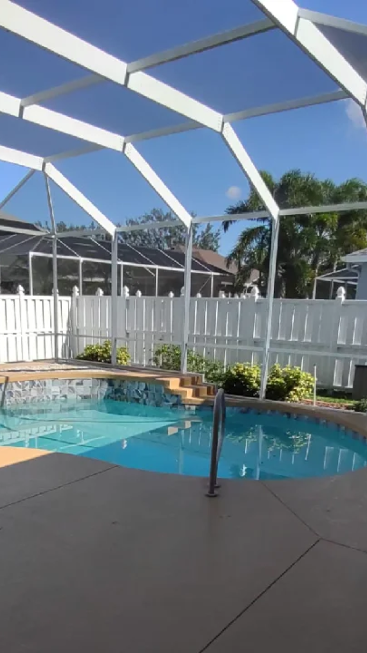 Clean pool area with a screened enclosure after pressure washing service