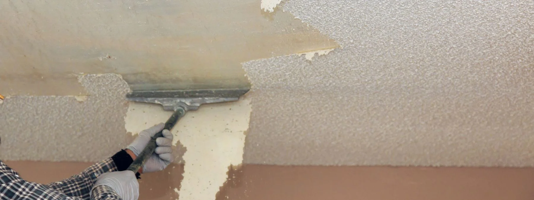 Professional painters in Sarasota applying orange paint on interior wall using rollers and protective suits