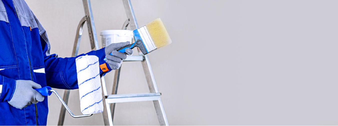 Professional painters in Sarasota applying orange paint on interior wall using rollers and protective suits